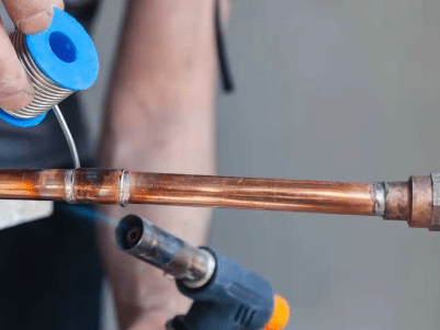 Plumber soldering pipe